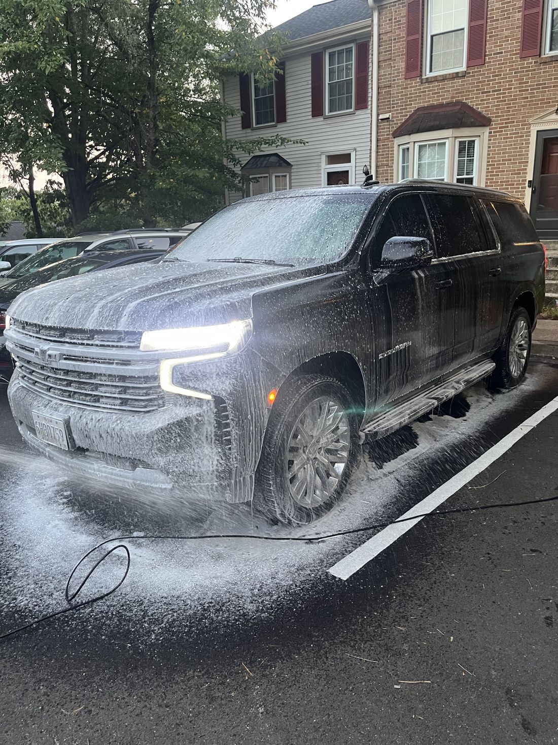 A black Chevy Suburban covered in white foam during the pre-wash